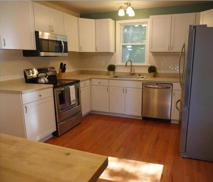A nice kitchen with recovered floors. Microwave, dishwasher, stove, and fridge intact.