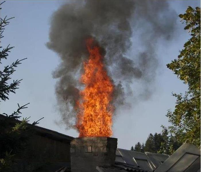 Flames shoot out of a house's chimney