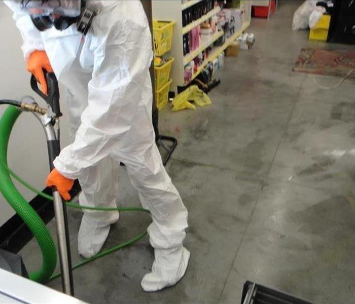 A worker in a hazmat suit cleans a warehouse